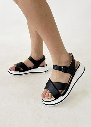 Чорні шкіряні босоніжки на білій танкетці.