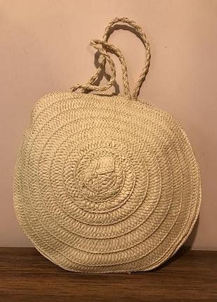 Кругла плетена сумка з короткою ручкою.