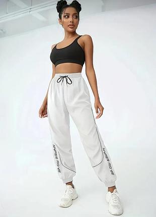 Джоггеры, спортивные штаны с светоотражающей надписью.