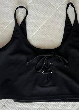 Укороченный черный топ с декоративными завязками.