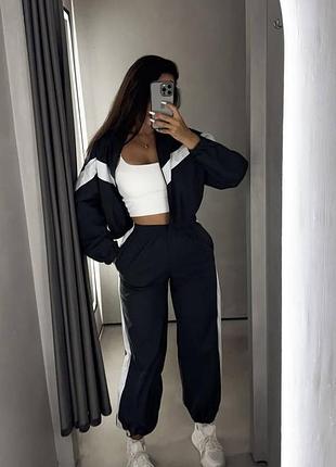 Стильный черный костюм с белыми контрастными вставками создает эффектный спортивный образ.