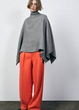 Накидка сірого кольору, йде оверсайзом , високий комір , є блискавка позаду