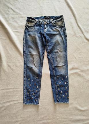 Женские синие джинсы с люверсами.
