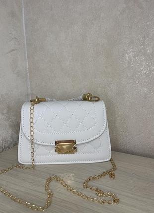 Елегантна біла сумочка зі стьобаним дизайном, золотою фурнітурою та ланцюжком. стильний акцент для будь-якого образу.