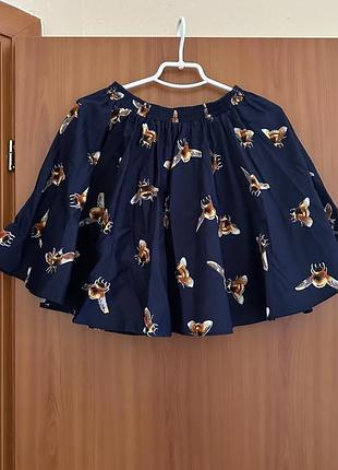 Легка розкльошена спідниця темно-синього кольору з оригінальним принтом — великими золотистими бджолами