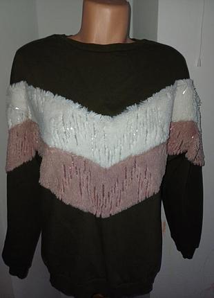 Женский свитшот темно-зеленого цвета с v-образными вставками белого и розового цветов, украшенными бахромой и блестками.