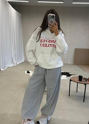 Зручний жіночий повсякденний костюм з тринитки на флісі оверсайз худі зі шнурком та написом спереду з кишенею кенгуру та штани вільного крою