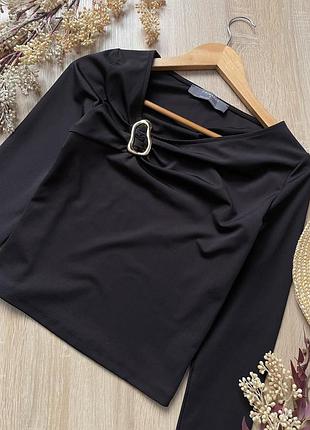 Вкорочена чорна блузка топ з акцентною брошкою золотистою і асиметричним декольте