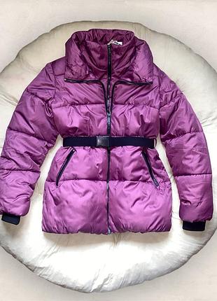 Стильна об’ємна куртка з високою горловиною, паском та подвійною застібкою.