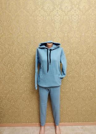 Женский теплый спортивный костюм из трехнитки на флисе с капюшоном и карманами.