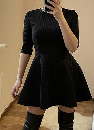 Чорна сукня з рукавами три чверті та спідницею-кльош.