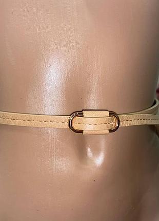 Тонкий бежевий ремінь із золотистою овальною пряжкою