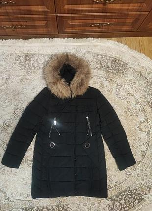 Б/у зимняя удлиненная куртка с капюшоном и натуральным мехом, черного цвета, два кармана на замках, застегивается на двустороннюю молнию и кномки.