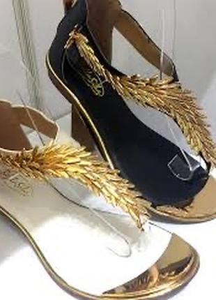 Босоніжки-сандалі з золотими металевими елементами.