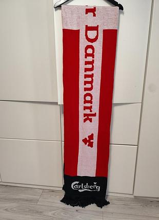 Шарф на изображении — это сувенирная продукция, связанная с датской пивоваренной компанией carlsberg.