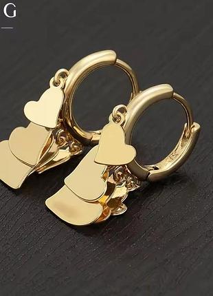 Золотисті сережки-кільця з підвісками у формі сердець