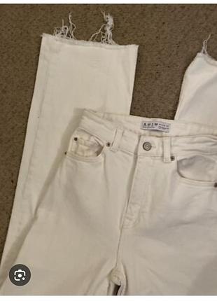 Джинсы молочного цвета с необработанным низом.