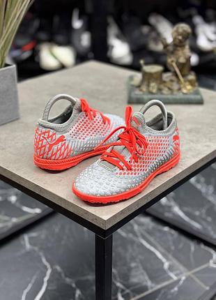 Футбольне взуття puma future 4.4 tt jr сріблястого кольору з яскраво-помаранчевими акцентами.