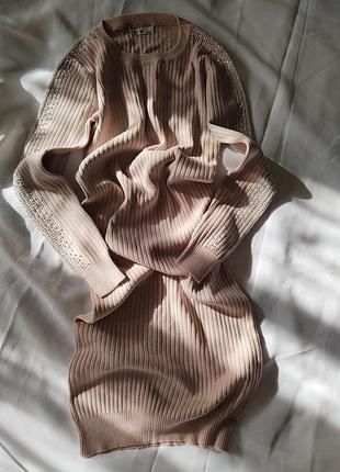 Бежевое с длинными рукавами платье, украшенное стразами по швам рукавов.