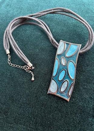 Прямокутний металевий кулон з емаллю синього та сірого кольорів на шнурі.