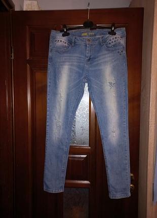 Джинсы женские голубые с потертостями и рваными элементами. декорированы металлическими шипами. размер l