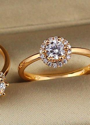 Кольцо xuping jewelry с белым камнем 5 мм на шесть креплений в кругу камешков р 19 золотистое