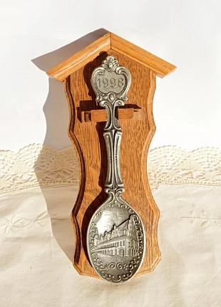 Интересно настенное панно в виде коллекционной ложки на дубовой подставке.