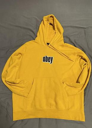 Жовтий худі, схожий на supreme та stussy, з назвою obey warp ii felpa