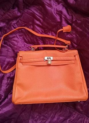 Сумка оранжевая с надписью hermes на зернистой коже и на золотом (цвет) замочке с 2 ключами на длинном ремне