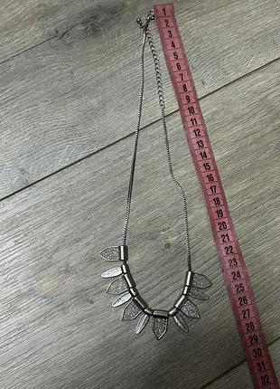 Сріблясте металеве кольє з підвісками у формі листя та блискучими вставками.