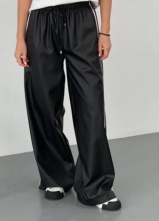 Стильні жіночі оверсайз штани палаццо на флісі вільного крою з еко шкіри на резинці зі шнурком та лампасами