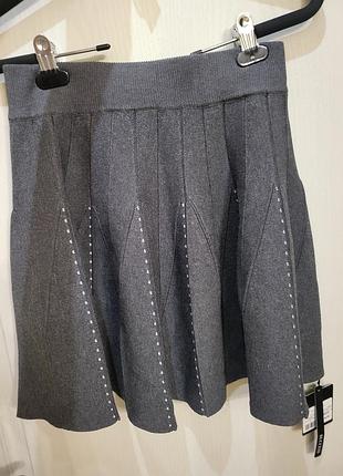 Серая вязаная мини-юбка с плиссировкой и декоративной строчкой.