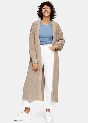 Подовжений жіночий в'язаний кардиган бежевого кольору.