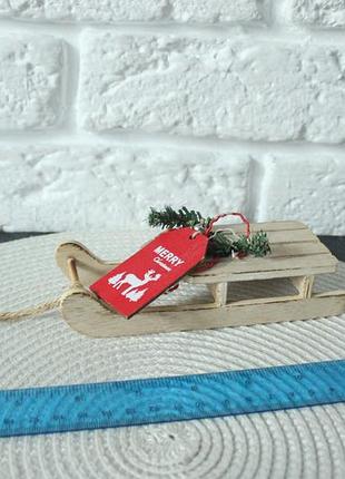Мініатюрні дерев'яні декоративні санки, які використовуються як новорічна підвіска або елемент композиції.