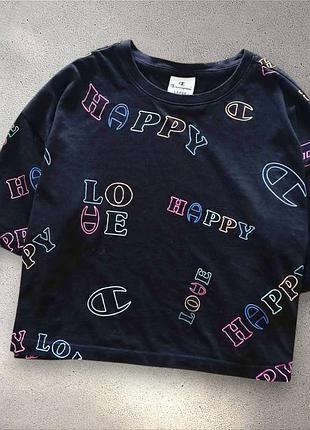 Черная футболка от бренда champion имеет свободный крой и украшена яркими графическими надписями