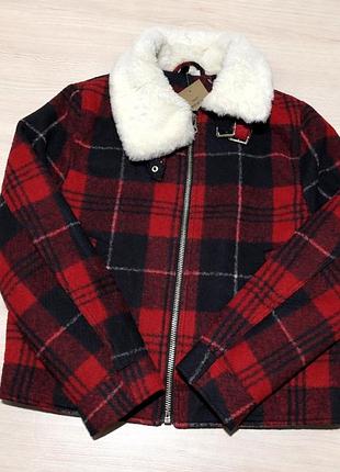 Червона клітчаста куртка з білим хутряним коміром на блискавці.