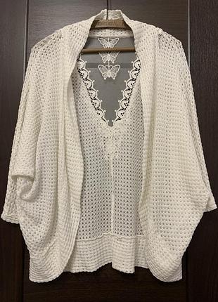 Це білий в'язаний кардиган у стилі бохо з мереживною вставкою з метеликами на спині.