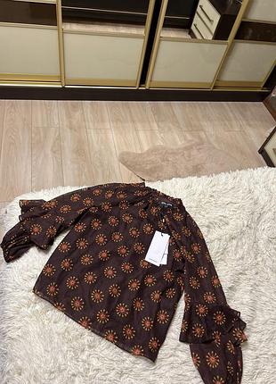 Женская блузка коричневого цвета с принтом в виде цветов выпущена брендом vero moda.