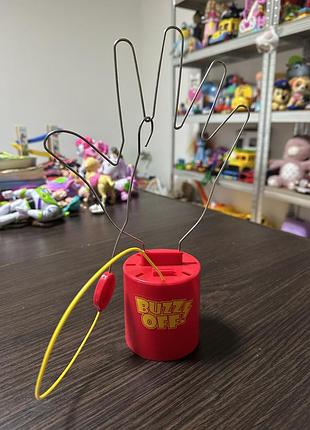 «buzz off» (або її аналог), де мета — провести металеве кільце вздовж дротяного контуру, не торкаючись його.