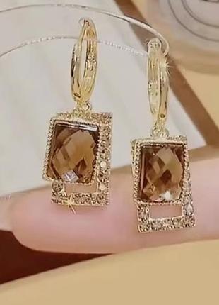 Сережки золотистого кольору з акріловим каменем