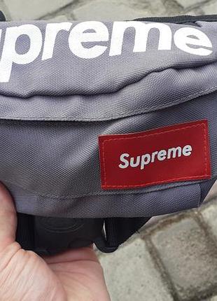 Серая поясная сумка (бананка) бренда supreme.