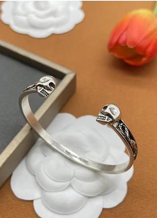 Браслет alexander mcqueen у сріблястому кольорі з черепами та гравіюванням.