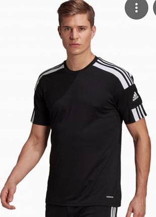 Черная футболка от бренда adidas имеет классический спортивный дизайн с белыми полосками на плечах и фирменным логотипом.спортивная футболка.