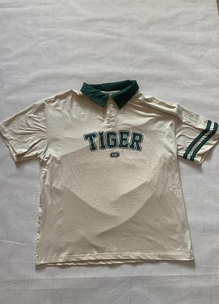Футболка-поло бежевого кольору з зеленим коміром та принтом «tiger me» належить до категорії стильних повсякденних сорочок поло