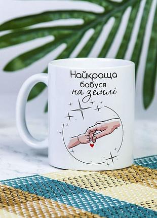 Біла керамічна чашка з дизайном "найкраща бабуся на землі"