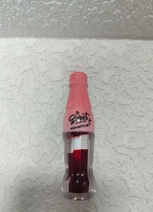 Це блиск для губ у формі пляшечки huda matte me, що забезпечує насичений колір та атласний фініш