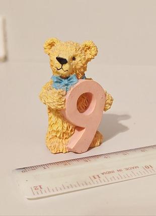 Коллекционная фигурка медвежонка, держащего цифру 9.