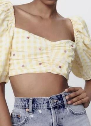 Це укорочений топ zara у жовто-білу клітку gingham з пишними рукавами та вишивкою.