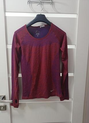 Это женская спортивная футболка с длинным рукавом nike dri-fit knit в красно-фиолетовом цвете.