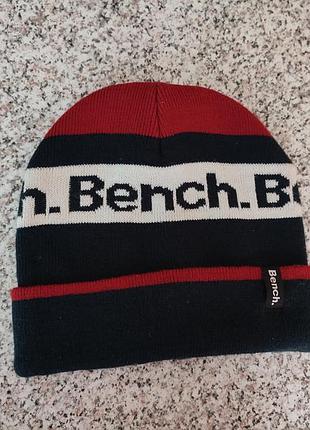Шапка спортивна для чоловіків фірми bench, розмір fits all. двостороння, матеріал акрил. колір темно синьо- бордовий з логотипом на білому фоні
